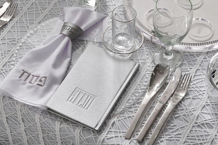 Painted Hardcover Leather & Lucite Haggadah Set in silver and white gold displayed with matching tabletop accessories on a patterned surface.