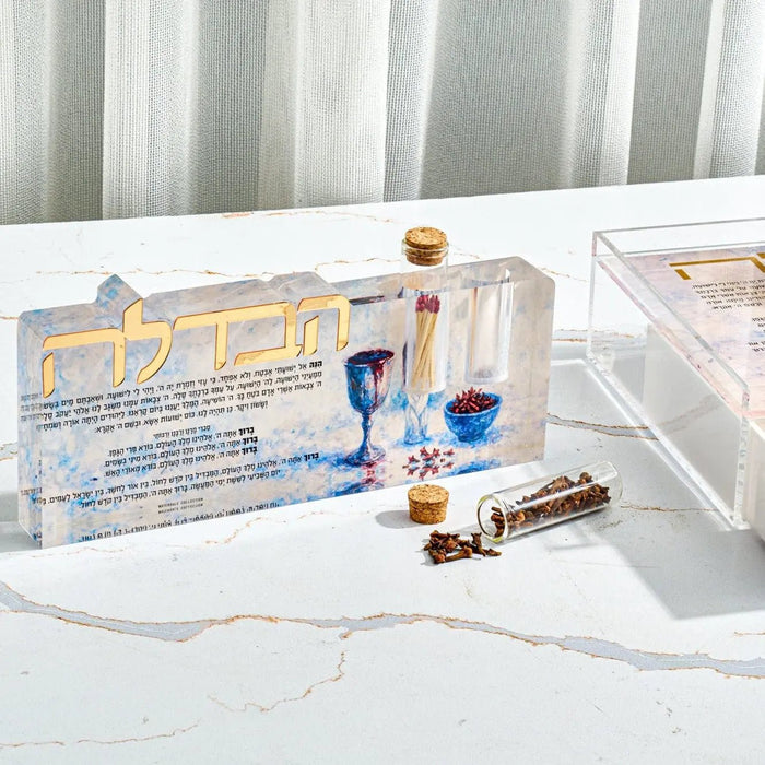 Painted Havdalah sculpture set with blue ceramic tray, candlestick, and ritual objects arranged on white marble surface.