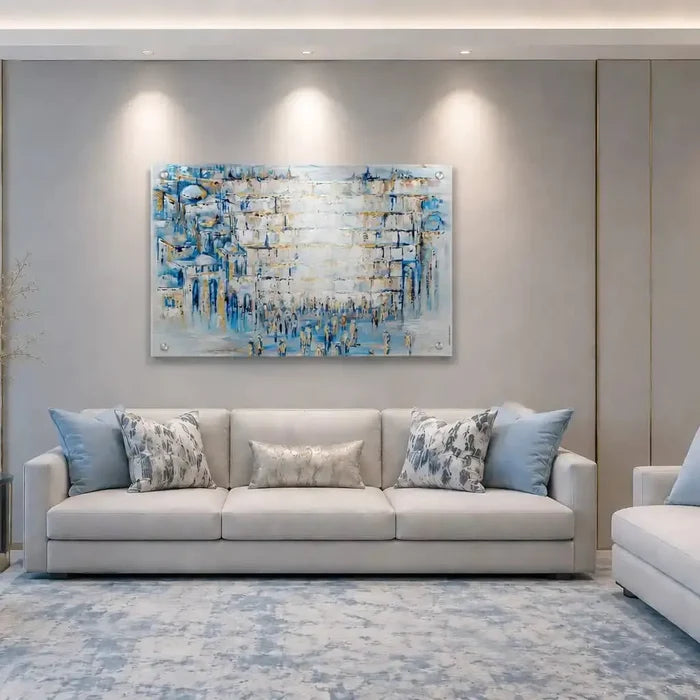 Painted Kosel by Yosefa featuring an abstract blue Jerusalem cityscape artwork displayed above a modern beige sofa with decorative pillows in a contemporary living room setting.