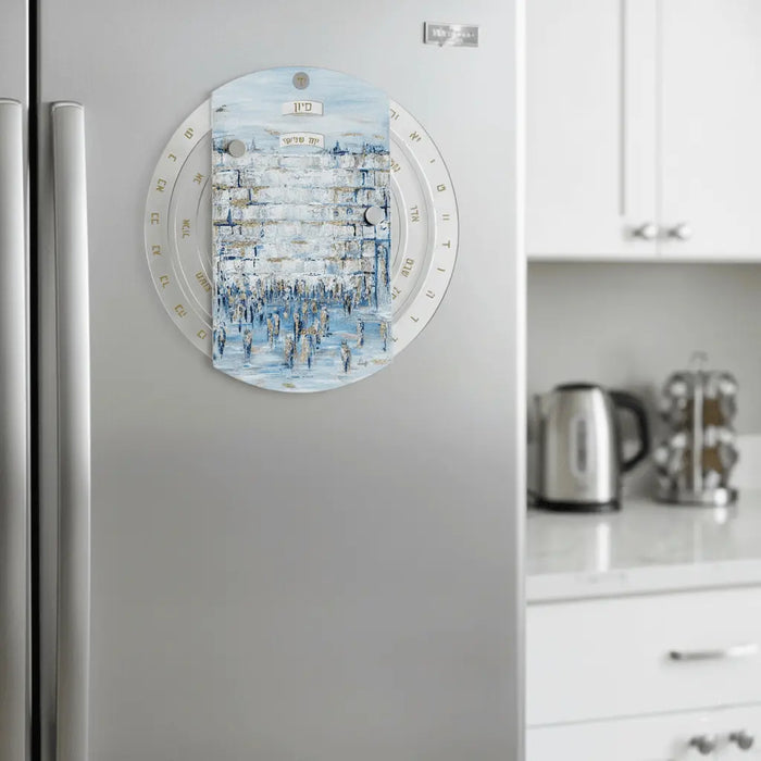 Painted Kosel Calendar Wheel magnet displayed on refrigerator, featuring blue watercolor design with Hebrew text and magnetic backing for easy display.