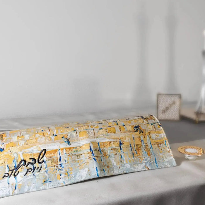 Gray and gold painted leather Challah cover by Waterdale Collection displayed on a bed with candles in background, perfect for Shabbat table.