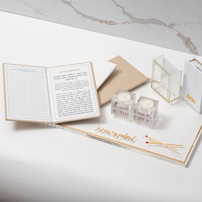 Leather Hadlokas Neiros booklet in cream and tan displayed open with candle-lighting cards and prayer book on white marble surface