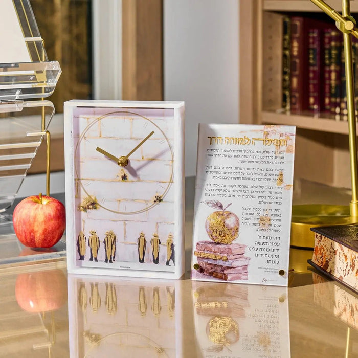 Painted Tefila L'Moreh Derech lucite card displaying Hebrew text and watercolor illustrations in warm tones, displayed on desk with apple and flowers