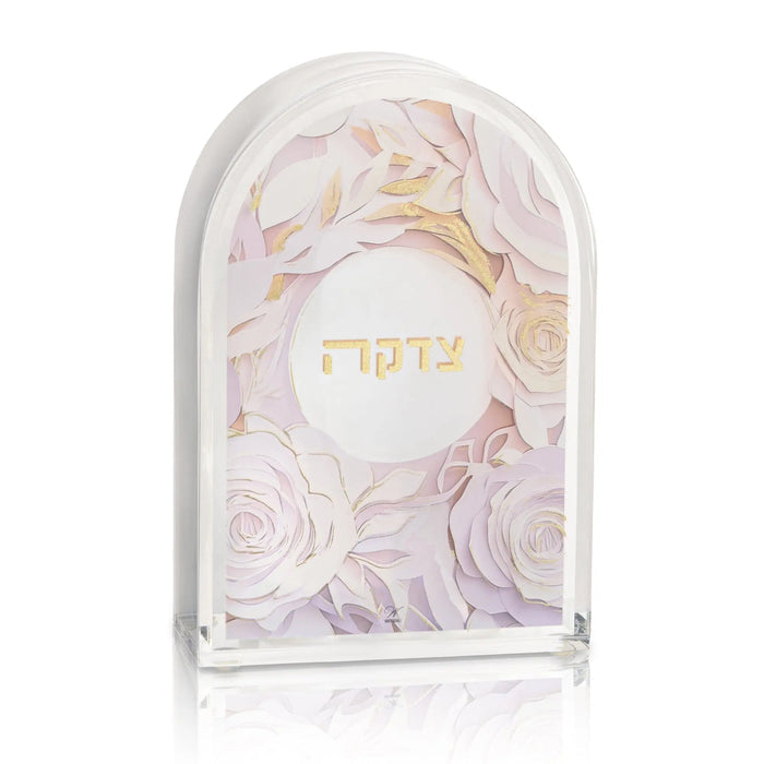 Papercut tzedakah box with delicate floral design in blush and gold tones, featuring Hebrew text on arched acrylic panel.