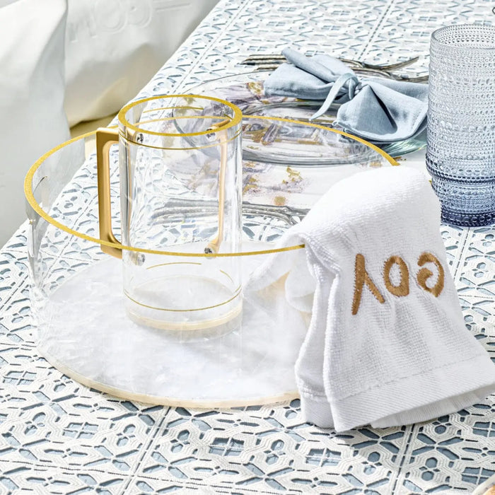 Pearlstone washing bowl and cup set in white marble finish with gold accents, displayed with white linens on decorative background.