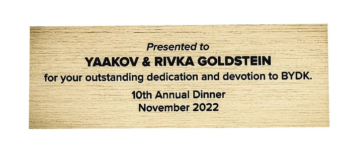 Gold personalization plate with black engraved text showing name and date, suitable for gift customization and dedication.