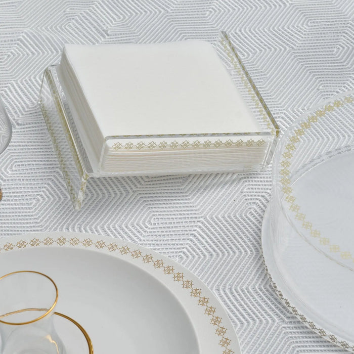 Waterdale Collection raised inspired napkin holder in white with gold metal accent trim, displayed on white tabletop with place settings