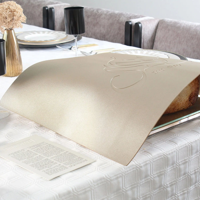 Cream leather Regal Embossed Challah Cover displayed on white bedding, showing elegant embossed design detail for Shabbat table.