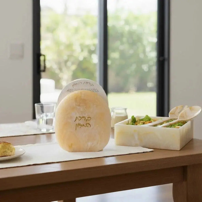 Cream resin bencher set displayed on wooden table with place settings, featuring embossed design for Shabbat and holiday entertaining.