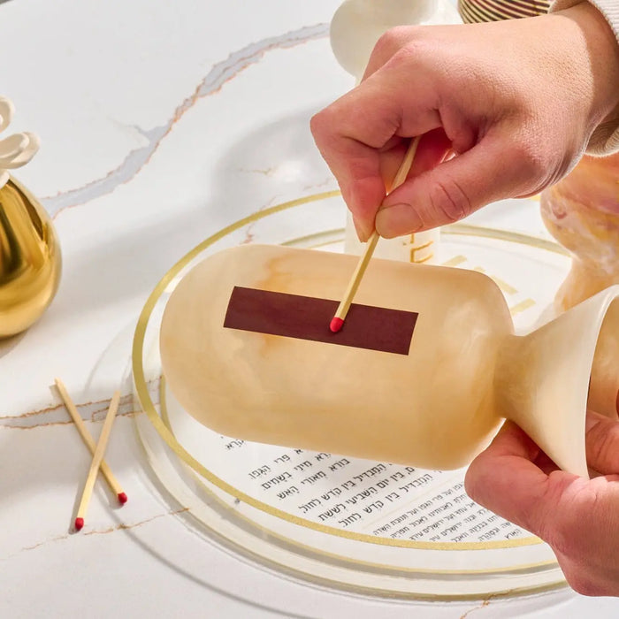 Cream and tan resin match cloche with wooden base and metal striker, displayed with scattered matches on white surface