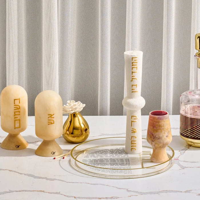 Cream resin match cloche with metal accents displayed among coordinating Shabbat candles and judaica items on a marble surface.