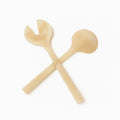 Crossed gold glitter resin salad servers with round bowl and fork ends on white background.