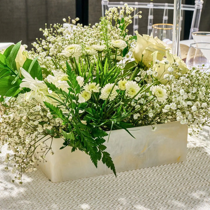 Gold-glitter resin square salad bowl from Waterdale Collection filled with white flowers, displayed outdoors on a patterned surface.