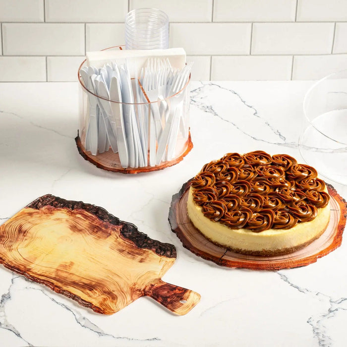 Wooden charcuterie board with round shape displayed with appetizers and serving utensils on marble countertop.
