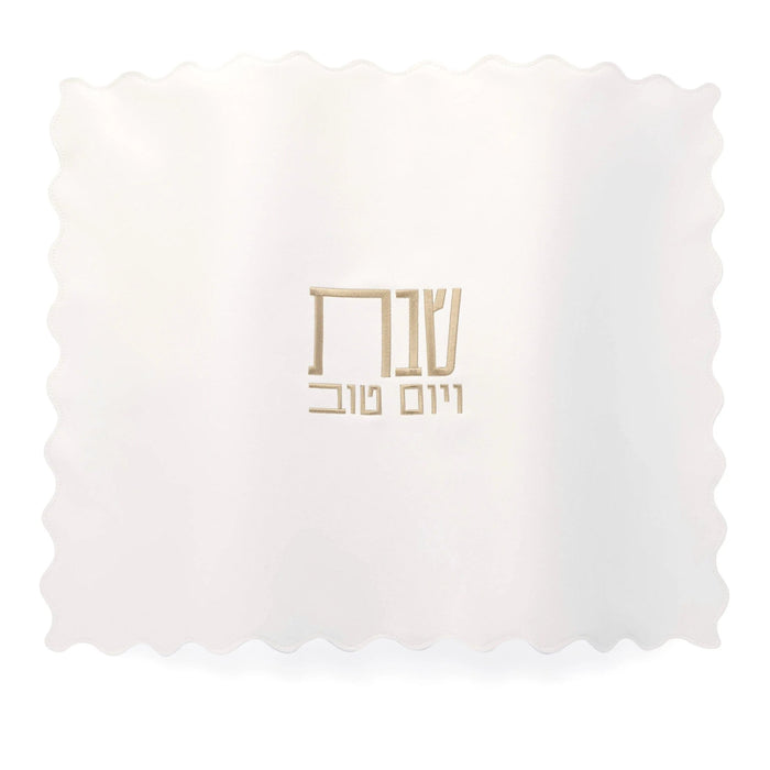 White leather scalloped edge challah cover with gold embroidered Hebrew text, perfect for Shabbat table settings.