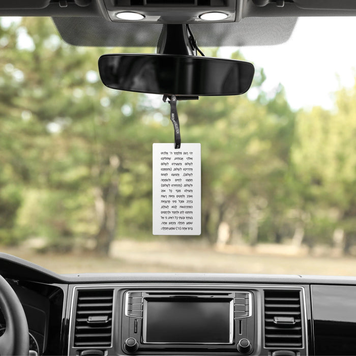 Scented Stone Tefillas Haderech Diffuser hanging from rearview mirror in car with forest background visible through windshield.