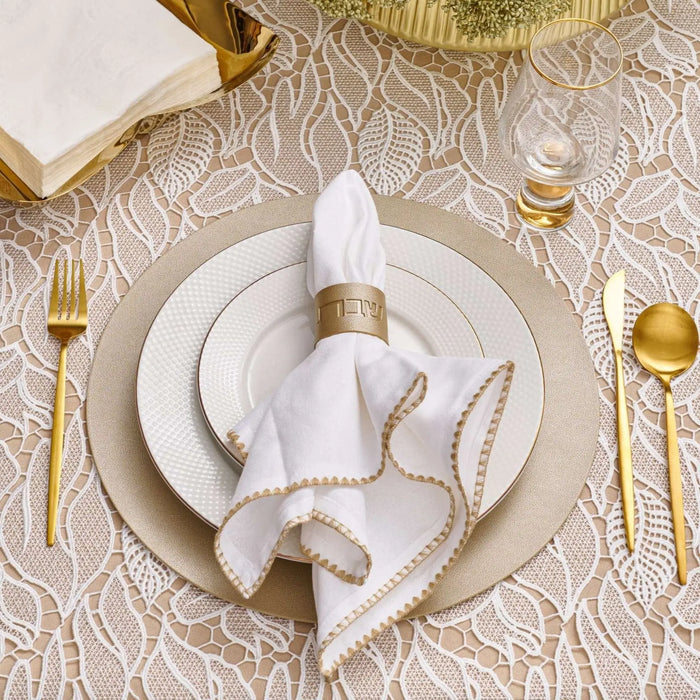 Gold leather napkin wraps displayed on white plates with elegant place setting for Shabbat dinner table decoration