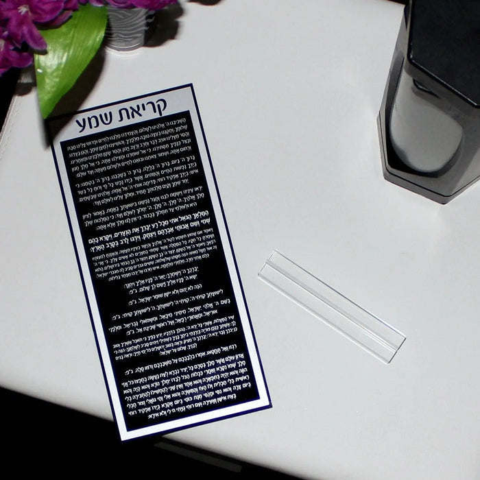 Black and silver lucite Shema prayer card displayed on white surface with Hebrew text visible, religious gift for bat mitzvah or Jewish occasions.
