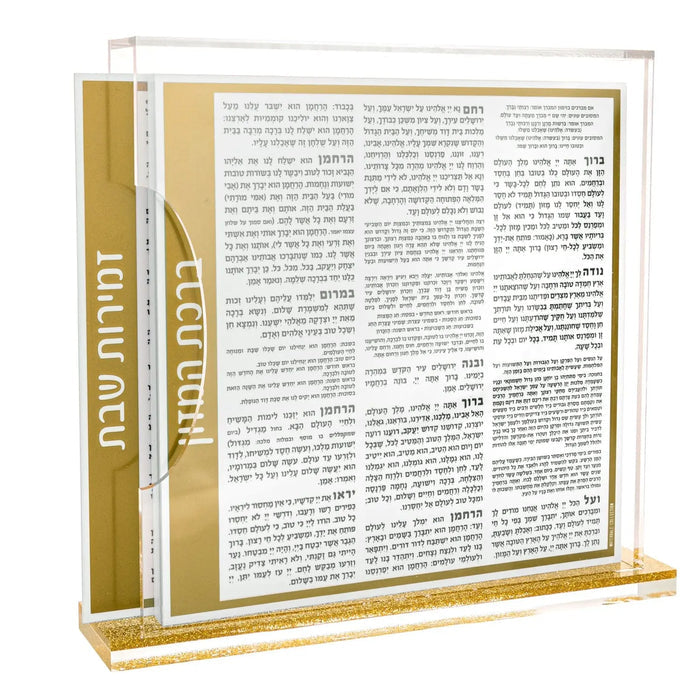 Gold and silver side opening bencher set with Zemiros text visible on open pages, displayed on tabletop for Shabbat use.