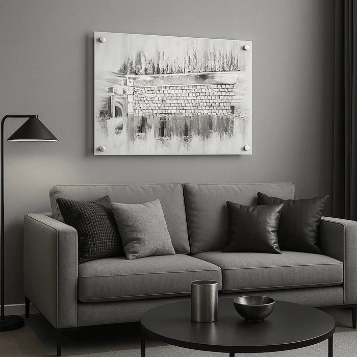 Silver Kosel at Winter painting displayed above a gray sofa, featuring a monochromatic winter Jerusalem scene in a minimalist gallery setting.