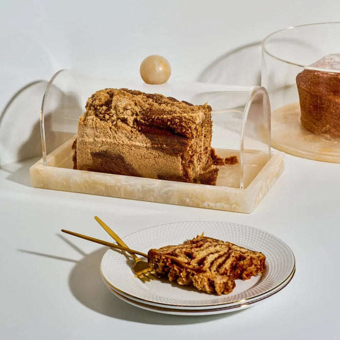 Small rectangular resin cake dome displaying sliced layered cake, shown with a plated pastry on white surface for elegant tabletop serving.