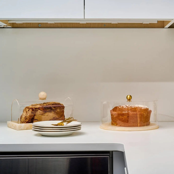 Small rectangular resin cake dome by Waterdale Collection displayed with a layered cake, featuring a warm amber tone and elegant design for serving and storage.