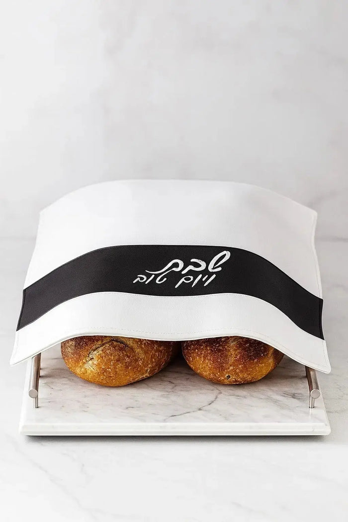 White leather Stripe Challah Cover with black band detail, displaying two braided challahs nestled inside for Shabbat.