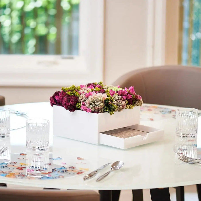 Succulent Bencher Set with faux floral arrangement in pink and green tones displayed on white table with open books and glasses nearby.