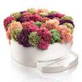 Succulent pink round vase bencher set with faux flowers in multiple shades of pink, purple, and green arranged in a white ceramic container with drawer base.