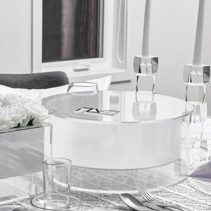 Suspended Matzah Box in clear lucite displayed on white bathroom counter with toiletries and mirror in background.