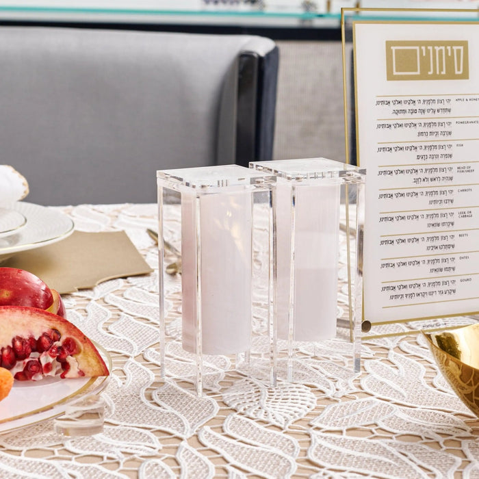 Transparent acrylic suspended salt shakers displayed on a table with menu cards and gold accents, part of the MetaLucite Pesach collection.