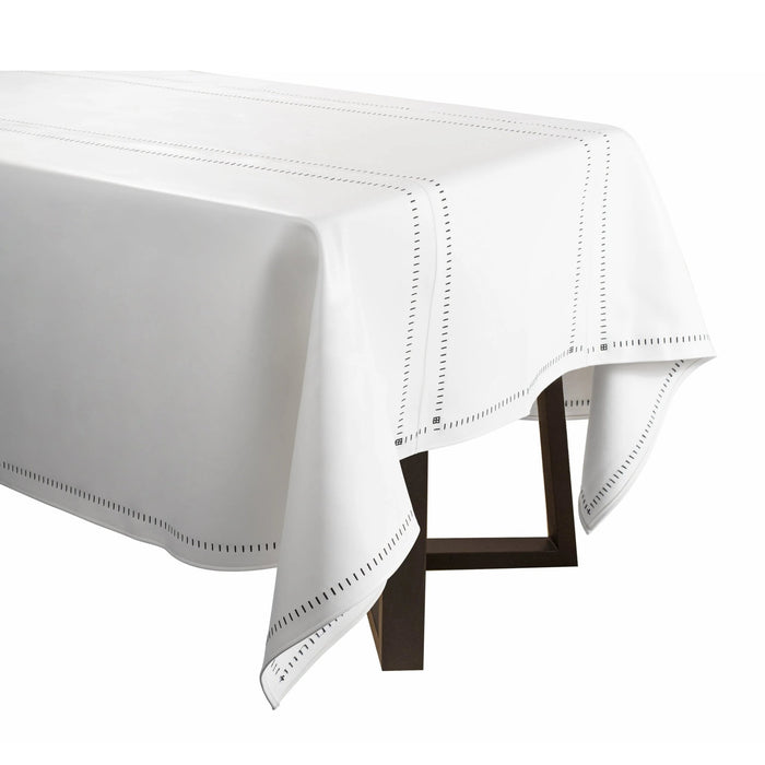 White leather tablecloth with hemstitch border detail, displayed on table with black chair legs visible underneath.