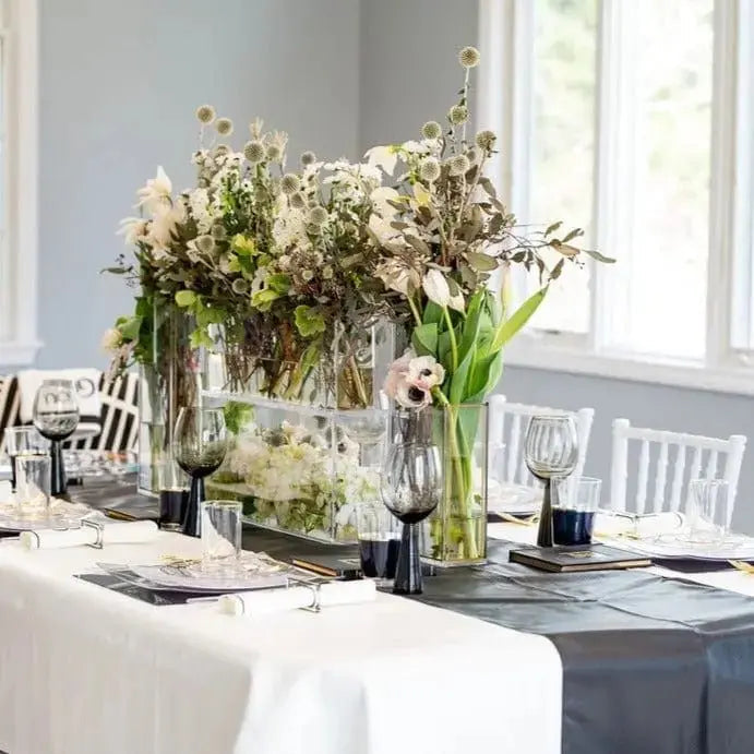 White leather tablecloth with black runner set elegantly on dining table with floral centerpiece and place settings