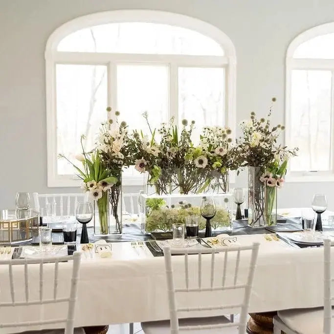 Cream linen tablecloth with matching runner on formal dining table set with floral centerpiece and place settings
