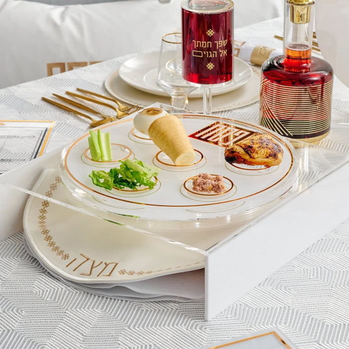 Tall Suspended Seder Plate in clear lucite displayed on a white tablecloth with Passover place settings and gold accents