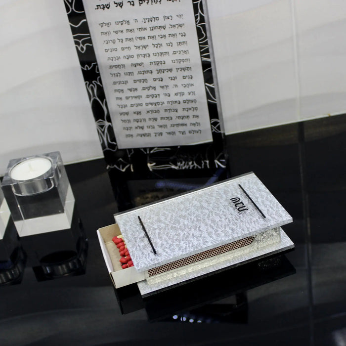 Marble and gold glitter traditional matchbox holder displayed on black surface with candles and religious text in background