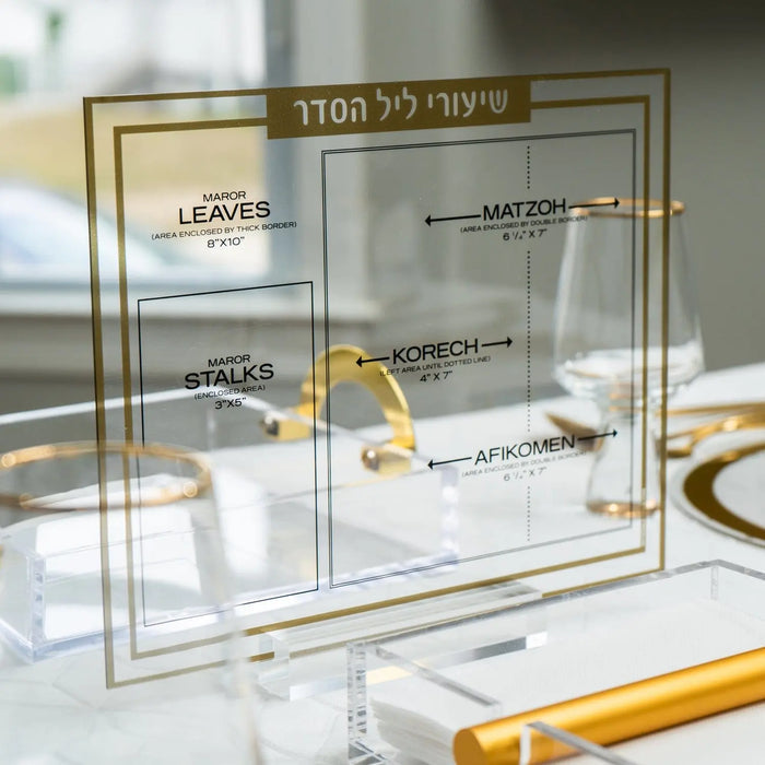 Traditional Shiurim gold and silver lucite card displayed on table with Hebrew text and organizational details visible.