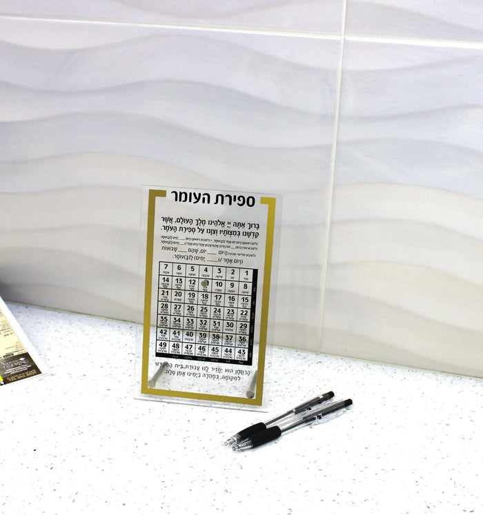 Gold and marble tabletop Sefiras Haomer plaque with numbered grid for counting the Omer during Pesach, displayed with pen.