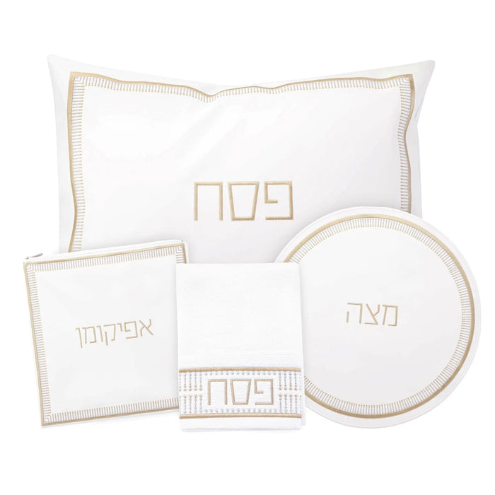 Trinket Pesach set with white leather placemats, napkin holder, plate charger, and coordinating gold-trimmed accessories arranged on white background.