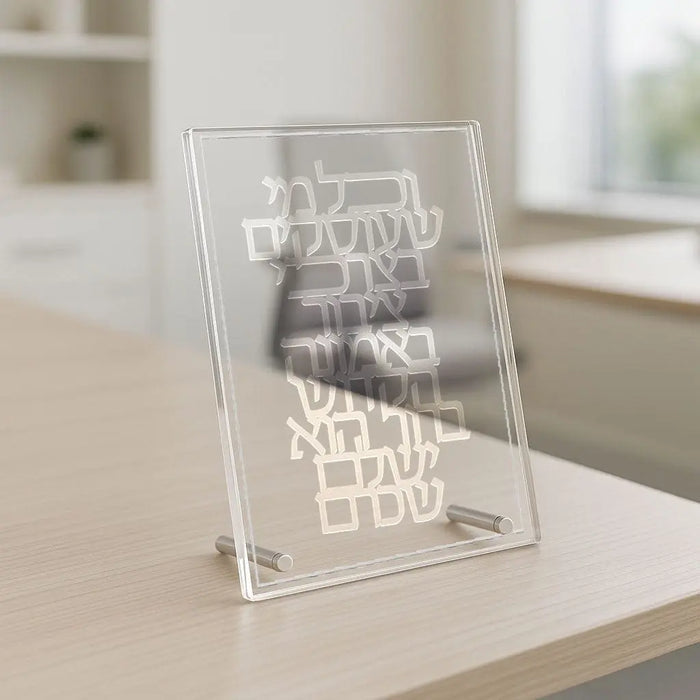 Clear acrylic V'chol Mi She'oskim tabletop plaque with white engraved Hebrew text on wooden surface in home setting.