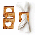 Two wooden napkin rings with carved circular cutouts, displayed holding white napkins, showing warm honey-toned wood finish and elegant tabletop styling.