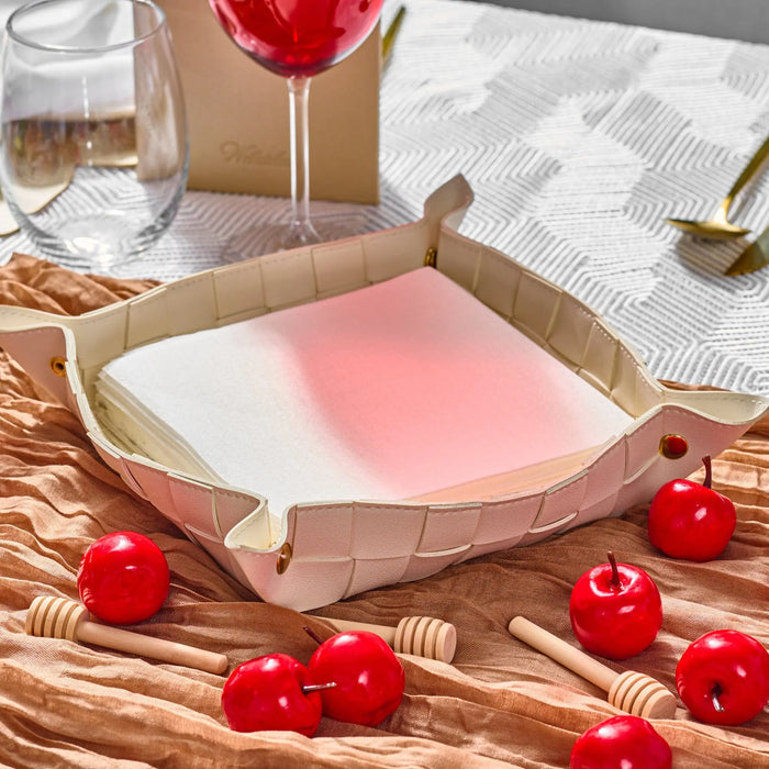 Woven leather napkin holder in natural tan with pink napkin, styled on table with candles, wine glass, and place setting for Shabbat dinner