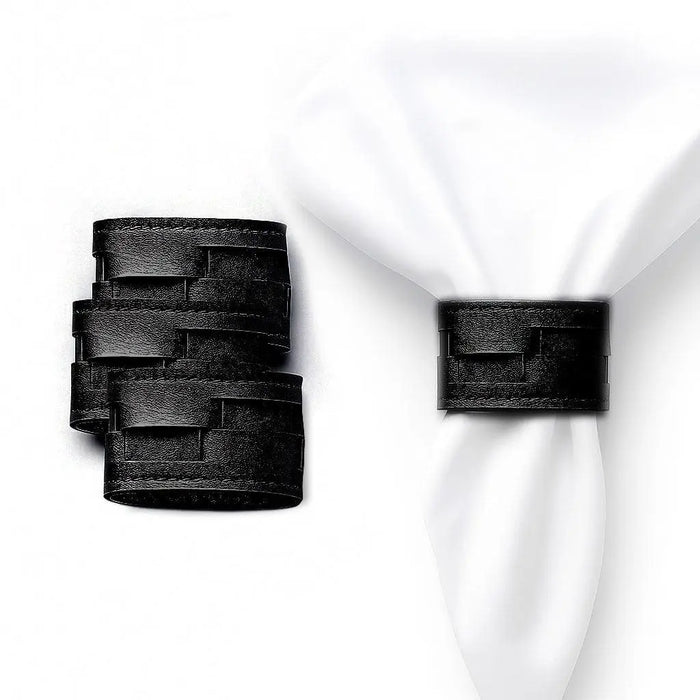 Black woven leather napkin wraps displayed on white napkins, showing textured woven design for elegant table settings