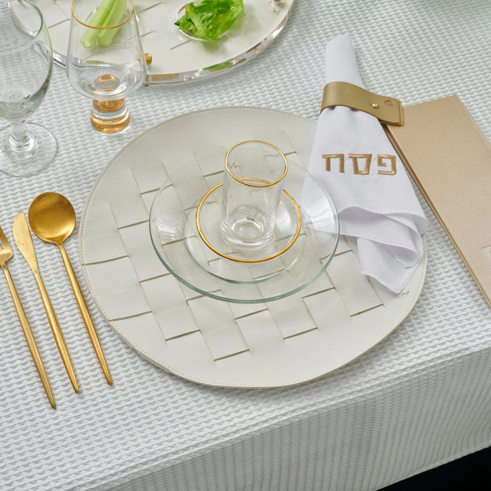 Woven leather round charger plate with silver border displayed on white table setting with gold flatware and glassware