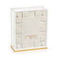 Cream woven tzedakah box with gold trim base, featuring small square openings on sides and top for charitable giving donations.